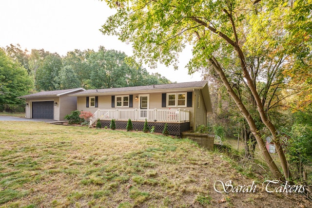 ranch-style house featuring a front yard, a garage, and a wooden deck