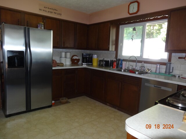 kitchen featuring appliances with stainless steel finishes, decorative backsplash, a textured ceiling, and sink