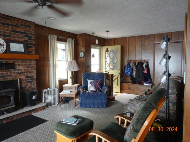 living room featuring a textured ceiling, carpet, wood walls, and ceiling fan