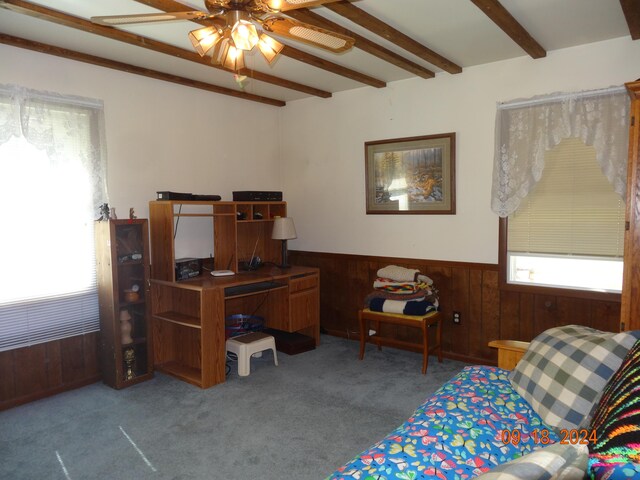 bedroom with carpet, beam ceiling, wood walls, and ceiling fan