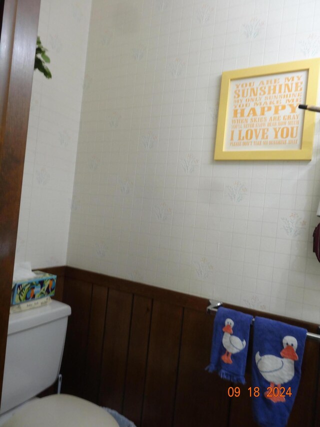 bathroom featuring wood walls and toilet