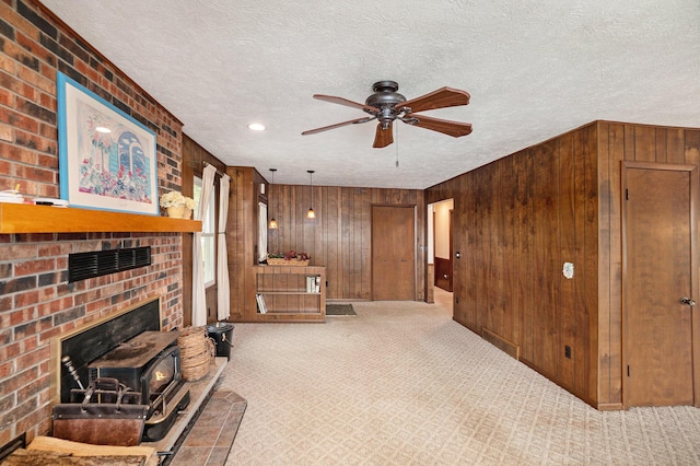5540 Cozy Point Dr, Newaygo, MI 49337 - unfurnished living room with wooden walls, a ceiling fan, carpet floors, a textured ceiling, and a fireplace