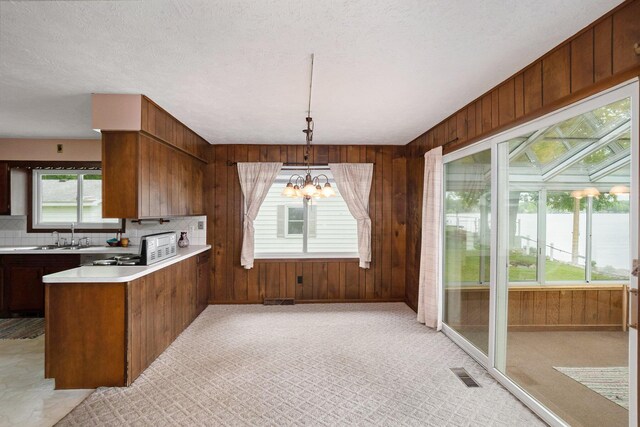 5540 Cozy Point Dr, Newaygo, MI 49337 - kitchen featuring light countertops, wood walls, a chandelier, a peninsula, and tasteful backsplash