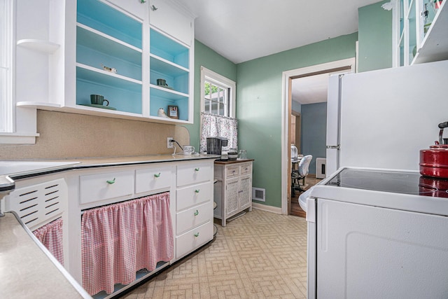 kitchen featuring white fridge, range, and white cabinets