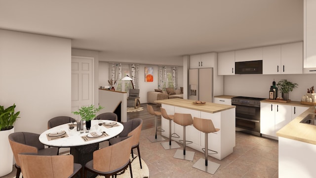 kitchen with a kitchen breakfast bar, refrigerator with ice dispenser, white cabinetry, and range with two ovens