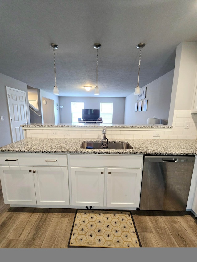 kitchen featuring wood-type flooring, stainless steel dishwasher, sink, decorative backsplash, and white cabinets