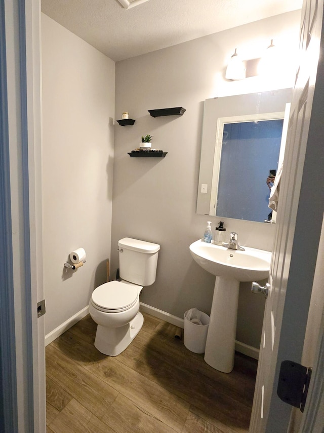 bathroom featuring a textured ceiling, toilet, and wood-type flooring