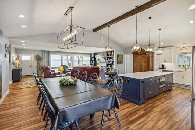 dining area featuring light hardwood / wood-style flooring and vaulted ceiling with beams