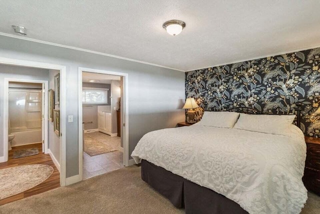 bedroom with ensuite bath, a textured ceiling, ornamental molding, and carpet