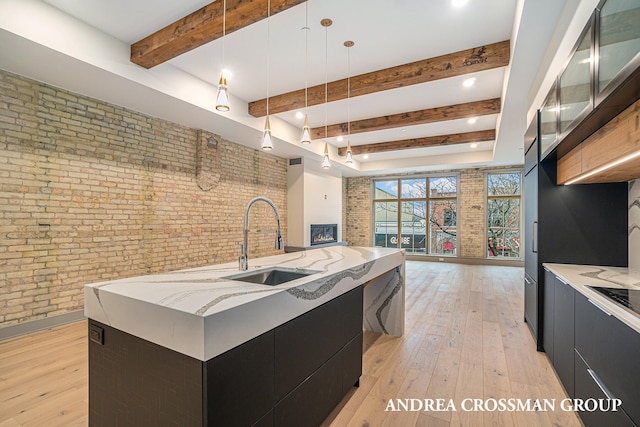 kitchen with a spacious island, beamed ceiling, brick wall, sink, and pendant lighting