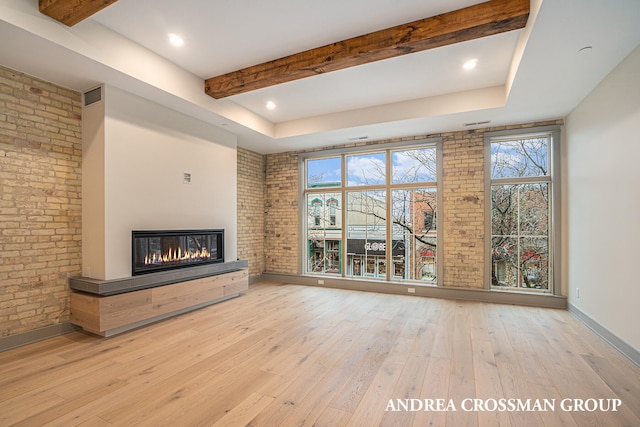 unfurnished living room featuring light hardwood / wood-style floors, brick wall, and plenty of natural light