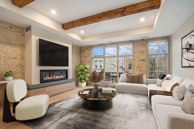 living room featuring hardwood / wood-style flooring, brick wall, and beam ceiling