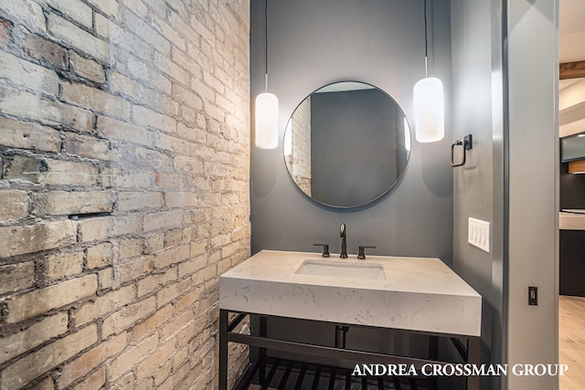 bathroom with vanity, hardwood / wood-style floors, and brick wall