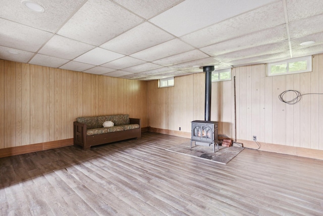 interior space featuring a wood stove, a paneled ceiling, wood walls, and hardwood / wood-style floors