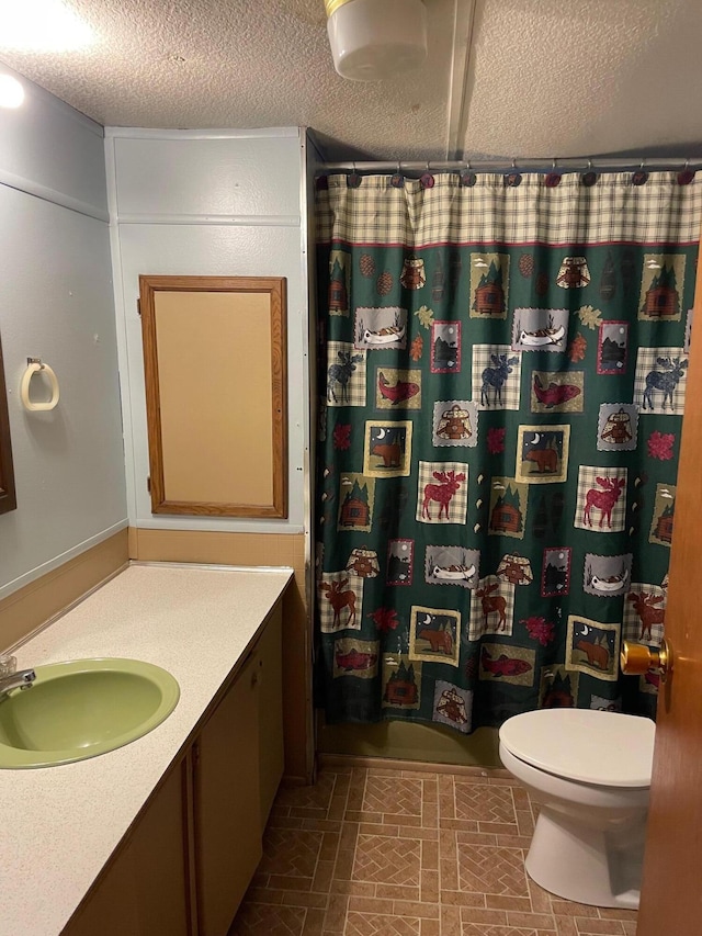 bathroom featuring curtained shower, toilet, a textured ceiling, and vanity