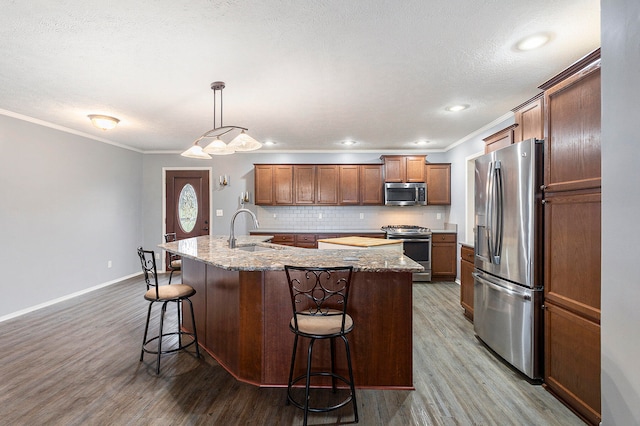 kitchen featuring a kitchen bar, sink, appliances with stainless steel finishes, and a kitchen island with sink