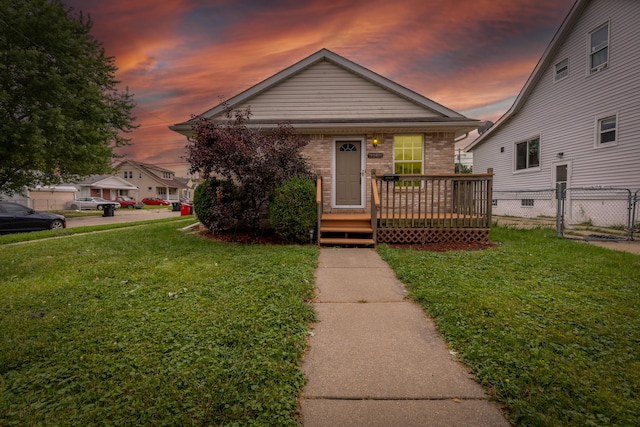 bungalow-style home with a wooden deck and a lawn