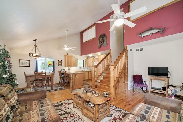 living room featuring high vaulted ceiling, light wood-type flooring, sink, and ceiling fan