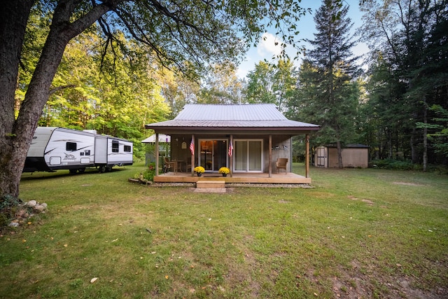 rear view of house with a yard, a porch, and a storage unit