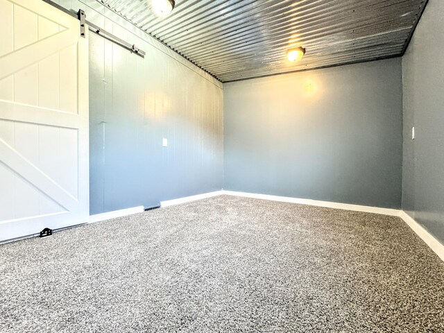 unfurnished room featuring carpet and a barn door