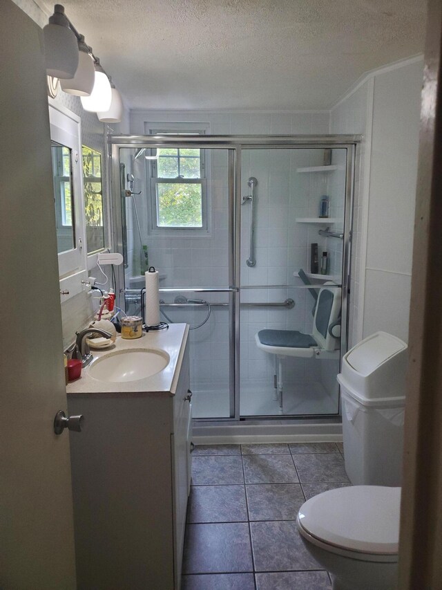 bathroom with a textured ceiling, vanity, an enclosed shower, toilet, and tile patterned floors