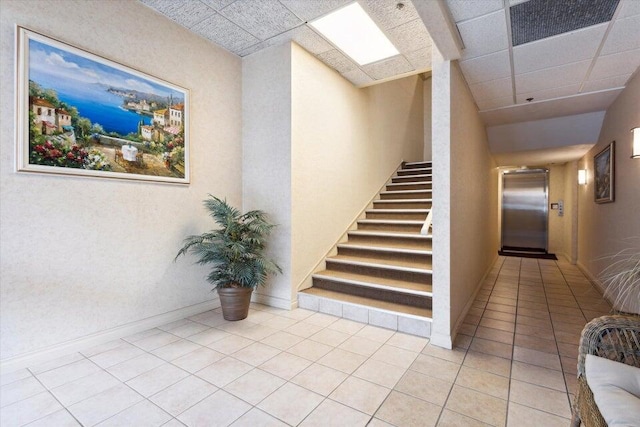 stairs with visible vents, a drop ceiling, elevator, a skylight, and tile patterned flooring