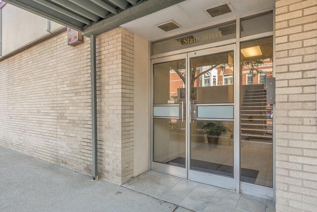 view of exterior entry featuring visible vents and brick siding