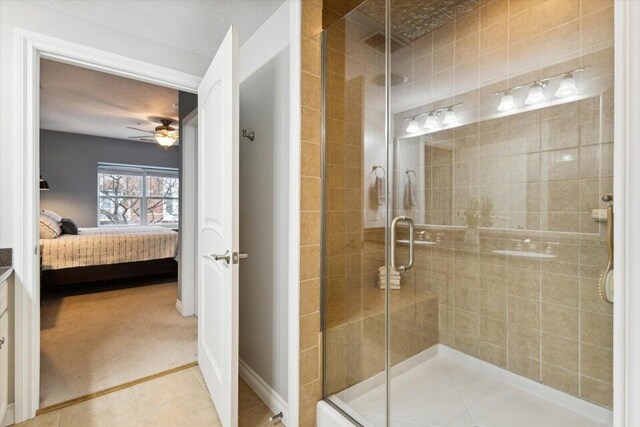 bathroom with tile patterned flooring, ceiling fan, and a shower with shower door