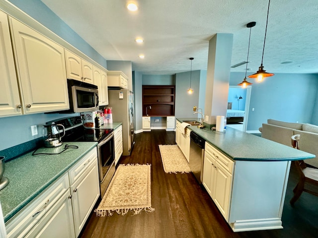 kitchen with a kitchen island, decorative light fixtures, appliances with stainless steel finishes, dark wood-type flooring, and sink