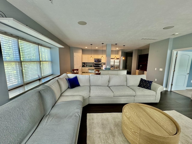 living area featuring baseboards, visible vents, light wood-type flooring, and a textured ceiling