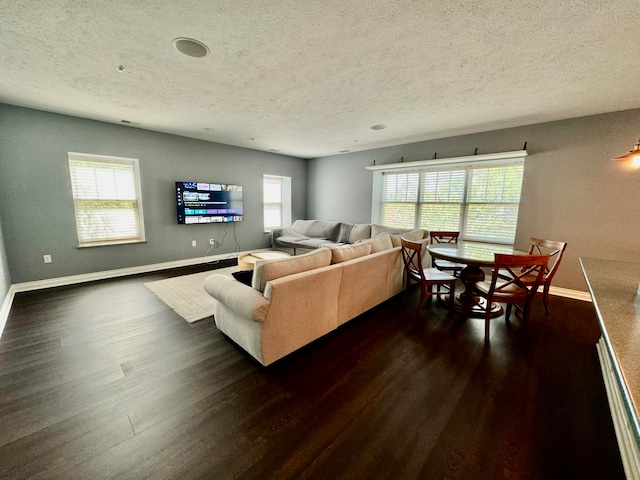 living room featuring dark wood-type flooring, a textured ceiling, and a healthy amount of sunlight