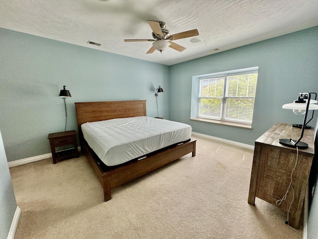 bedroom with a textured ceiling, baseboards, visible vents, and light carpet