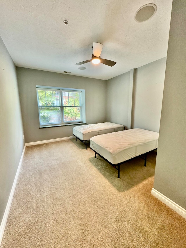 bedroom featuring a textured ceiling, ceiling fan, and carpet flooring