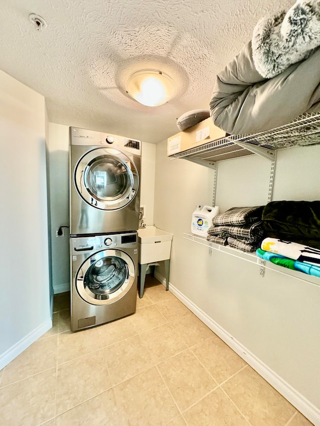 laundry area with light tile patterned floors, a textured ceiling, and stacked washer and clothes dryer