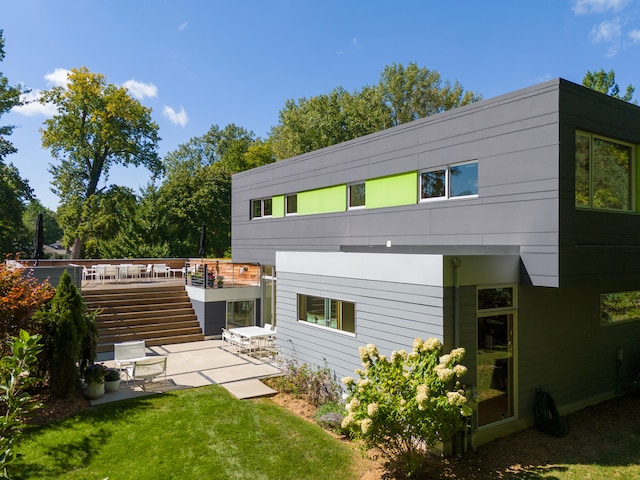 back of property with a wooden deck, a yard, and a patio