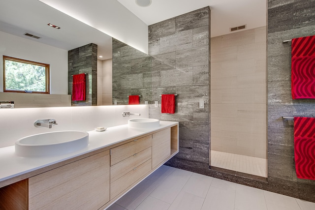 bathroom featuring backsplash, walk in shower, vanity, tile walls, and tile patterned flooring