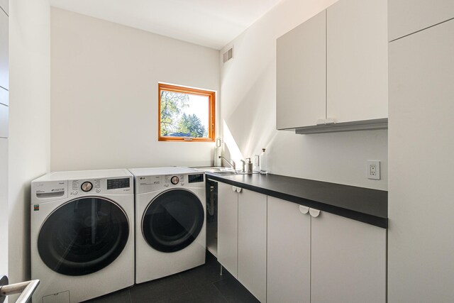 clothes washing area with washer and clothes dryer, cabinets, and sink