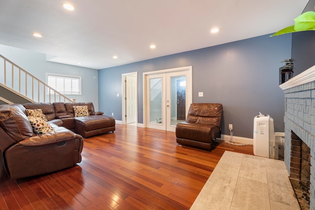 living room featuring french doors, a brick fireplace, and hardwood / wood-style flooring