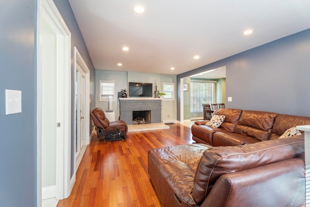 living room with a brick fireplace and light hardwood / wood-style floors