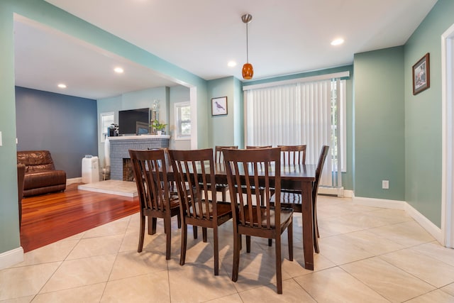 dining room with a brick fireplace and light hardwood / wood-style floors