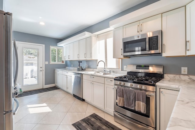 kitchen featuring white cabinetry, light stone counters, sink, appliances with stainless steel finishes, and light tile patterned flooring