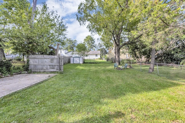 view of yard featuring a storage unit, an outbuilding, and a fenced backyard