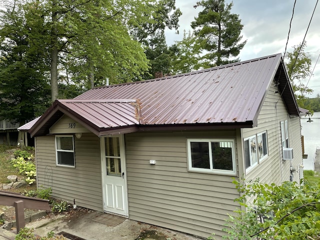 back of house with cooling unit and metal roof