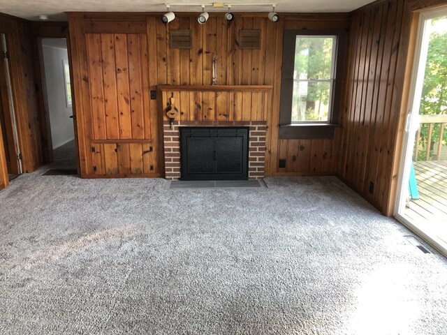 unfurnished living room with carpet flooring, a fireplace, and wooden walls