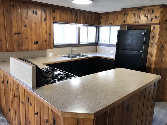 kitchen featuring black appliances, wood-type flooring, kitchen peninsula, and sink