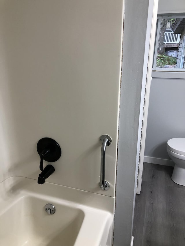 bathroom with a tub, wood-type flooring, and toilet