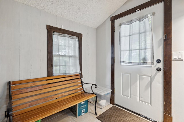 doorway featuring vaulted ceiling, a textured ceiling, and tile patterned flooring