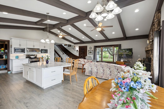 kitchen with hanging light fixtures, ceiling fan with notable chandelier, appliances with stainless steel finishes, and white cabinets