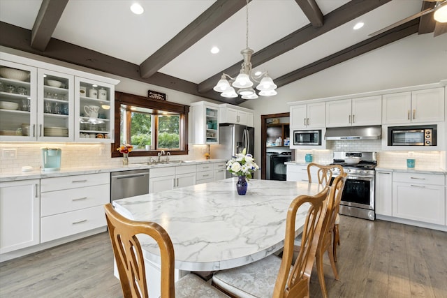 kitchen with backsplash, an inviting chandelier, stainless steel appliances, pendant lighting, and vaulted ceiling with beams