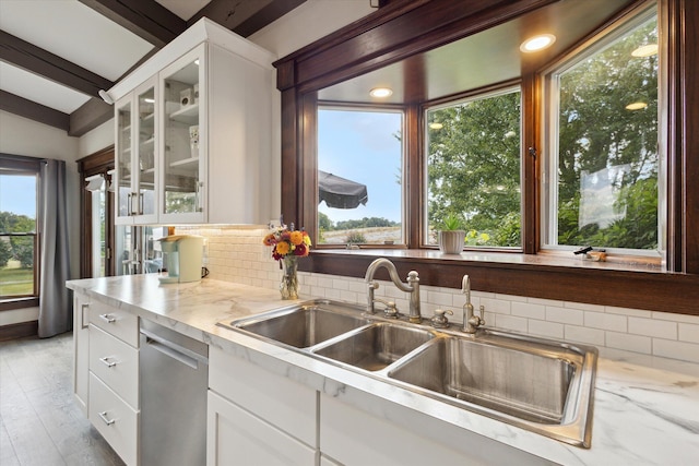 kitchen with tasteful backsplash, stainless steel dishwasher, white cabinets, and light hardwood / wood-style floors